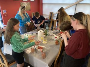 A group of young people gathered around a table making mocktails with a youth worker in The Devil's Porridge Museum's café.