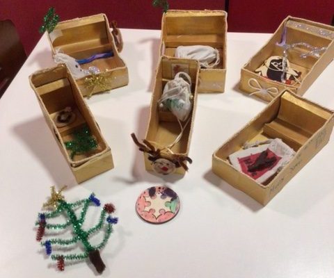 An assortment of Christmas crafts. This includes a pipe cleaner Christmas tree and some small Christmas sleighs.