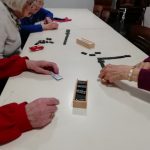Some members of Cordite Club sat around a table playing dominos.