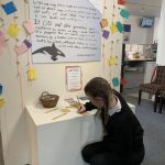 A student writing in The Devil's Porridge Museum's climate change exhibition area.