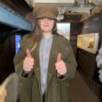 A student with their thumbs up dressing up in a military style hat and coat.