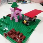 A pig made out of Lego bricks with a car and a tree.