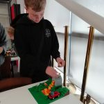 A young person putting the final touches to a Lego design.