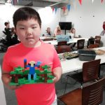 A young person proudly holding their Lego build.